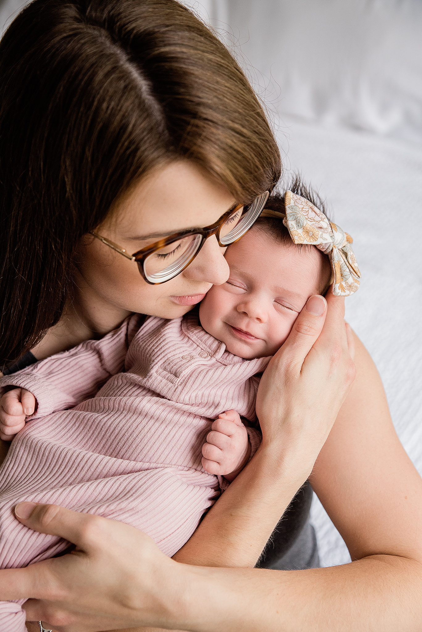 newborn baby girl smiling in mamas arms in home newborn session yeg