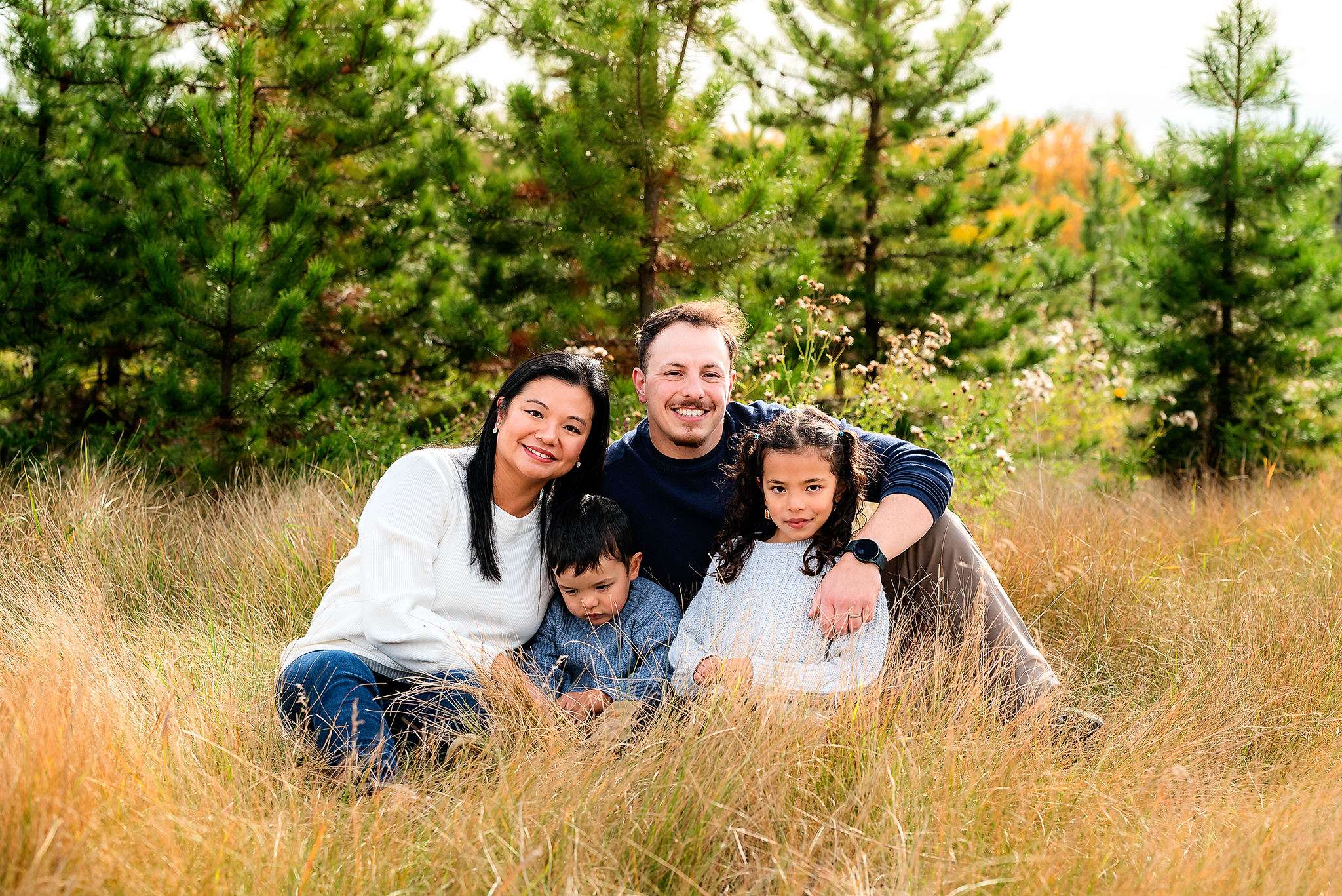 family of four sitting in tall grass outdoor family fall photo session strathcona county ab