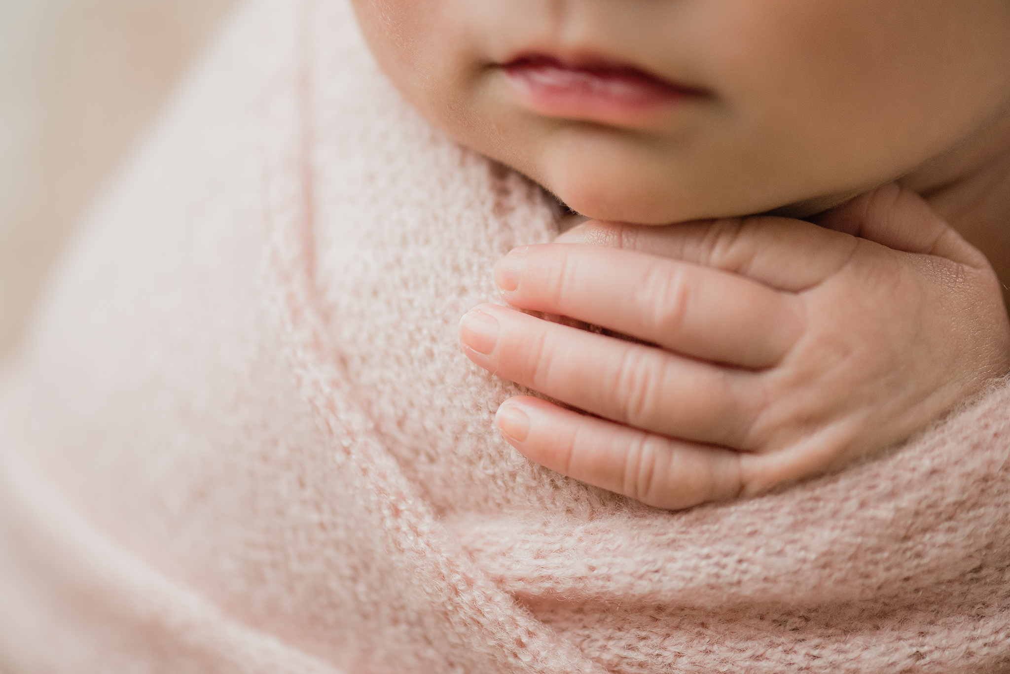 close up macro photo detail shot babys fingers resting on soft wrap under babys chin in home posed newborn photo session edmonton ab