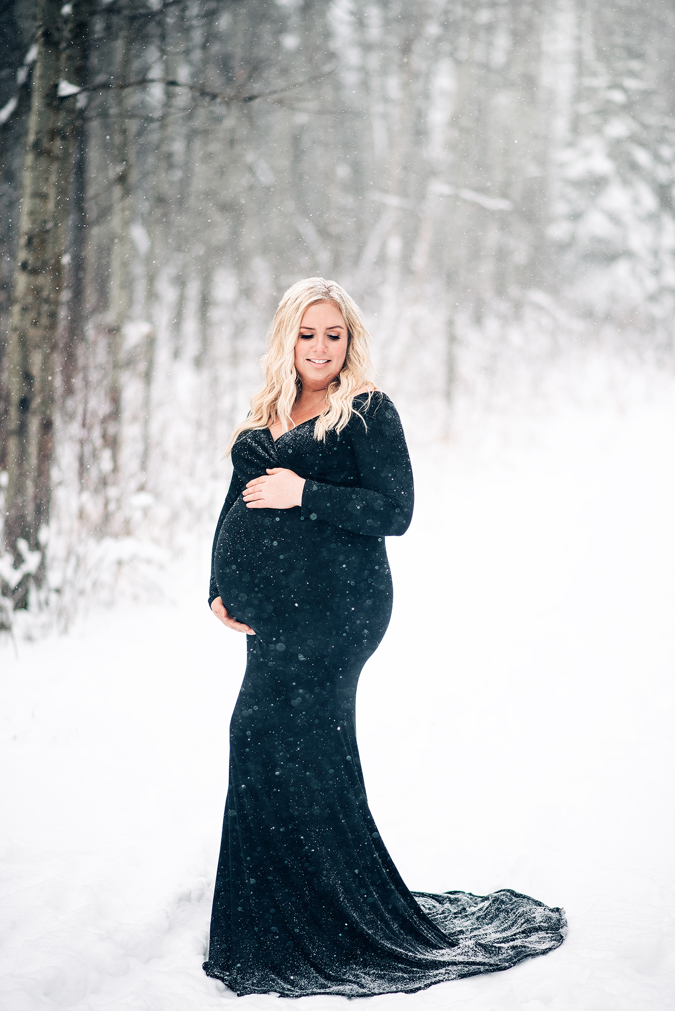 expecting mama holding pregnant belly smiling snowing winter maternity photo shoot yeg