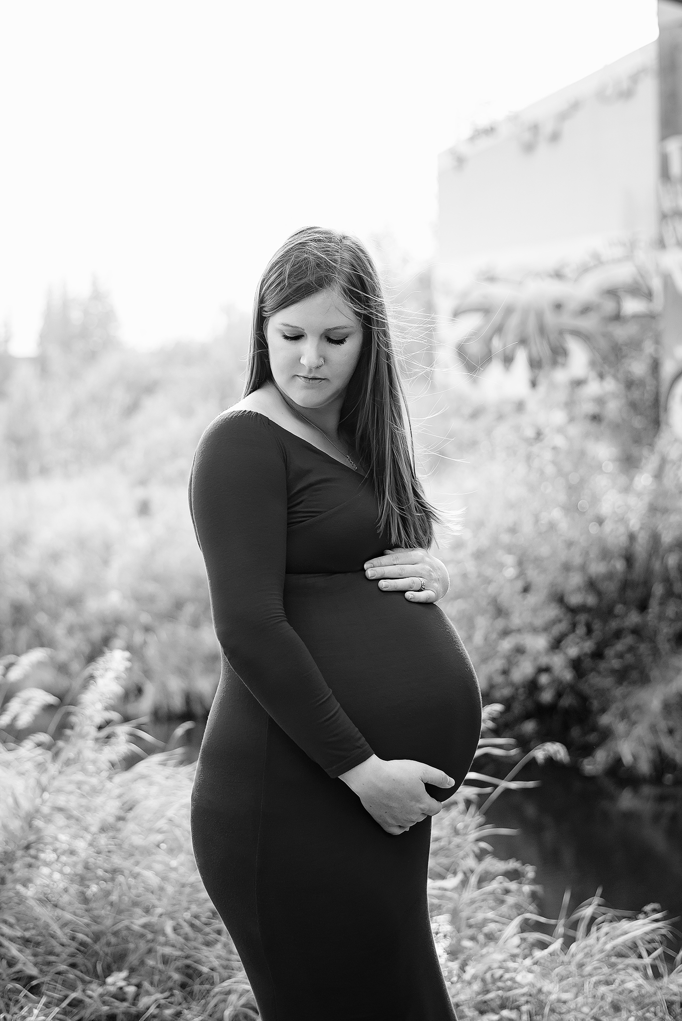 expectant mother looks past shoulder cradling belly edmonton maternity photographer