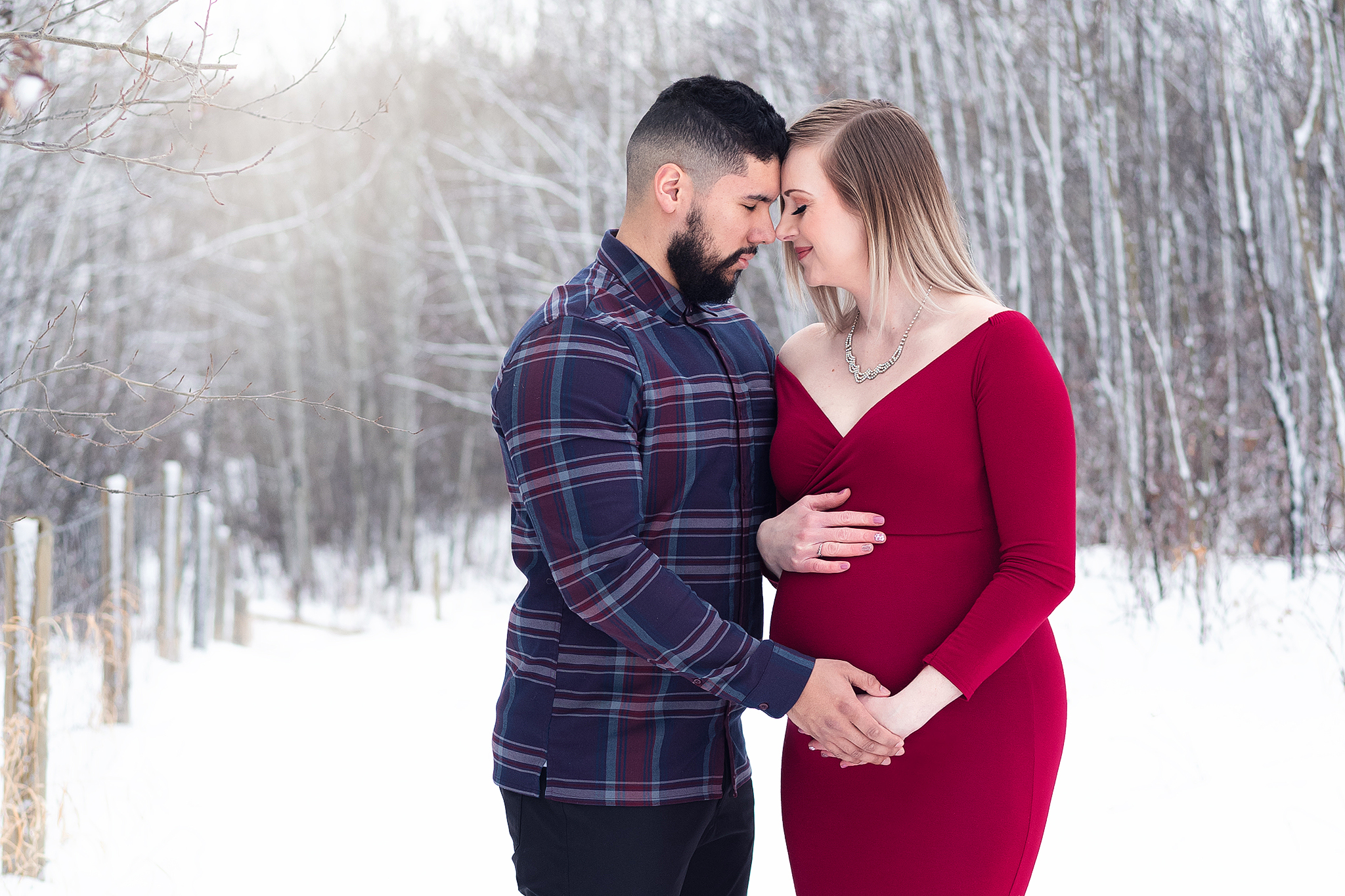 husband and wife stand in snow maternity photo session sherwood park