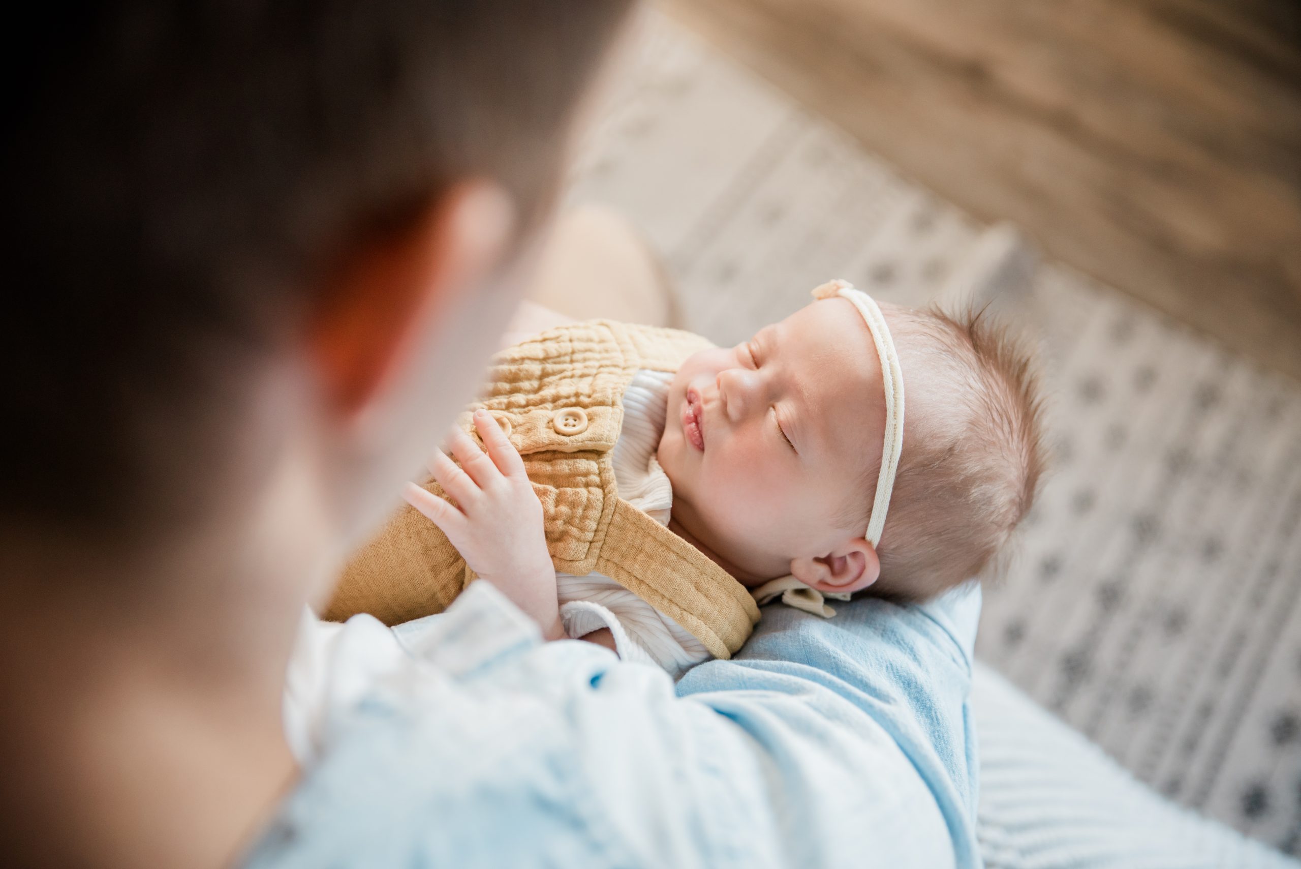 over the shoulder look at baby girl in dads arms edmonton lifestyle newborn photographer