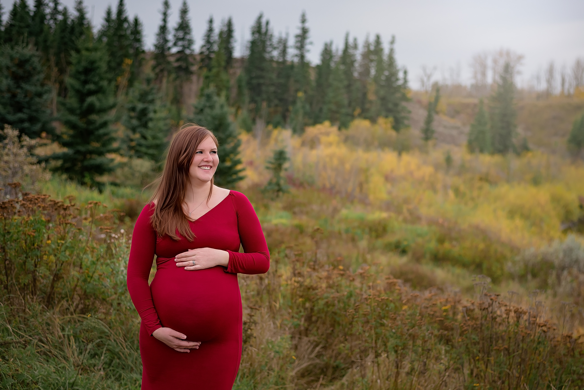 pregnant woman smiles holding belly outdoor maternity photoshoot yeg